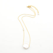 Gold necklace with a large pearl pendant on a white background