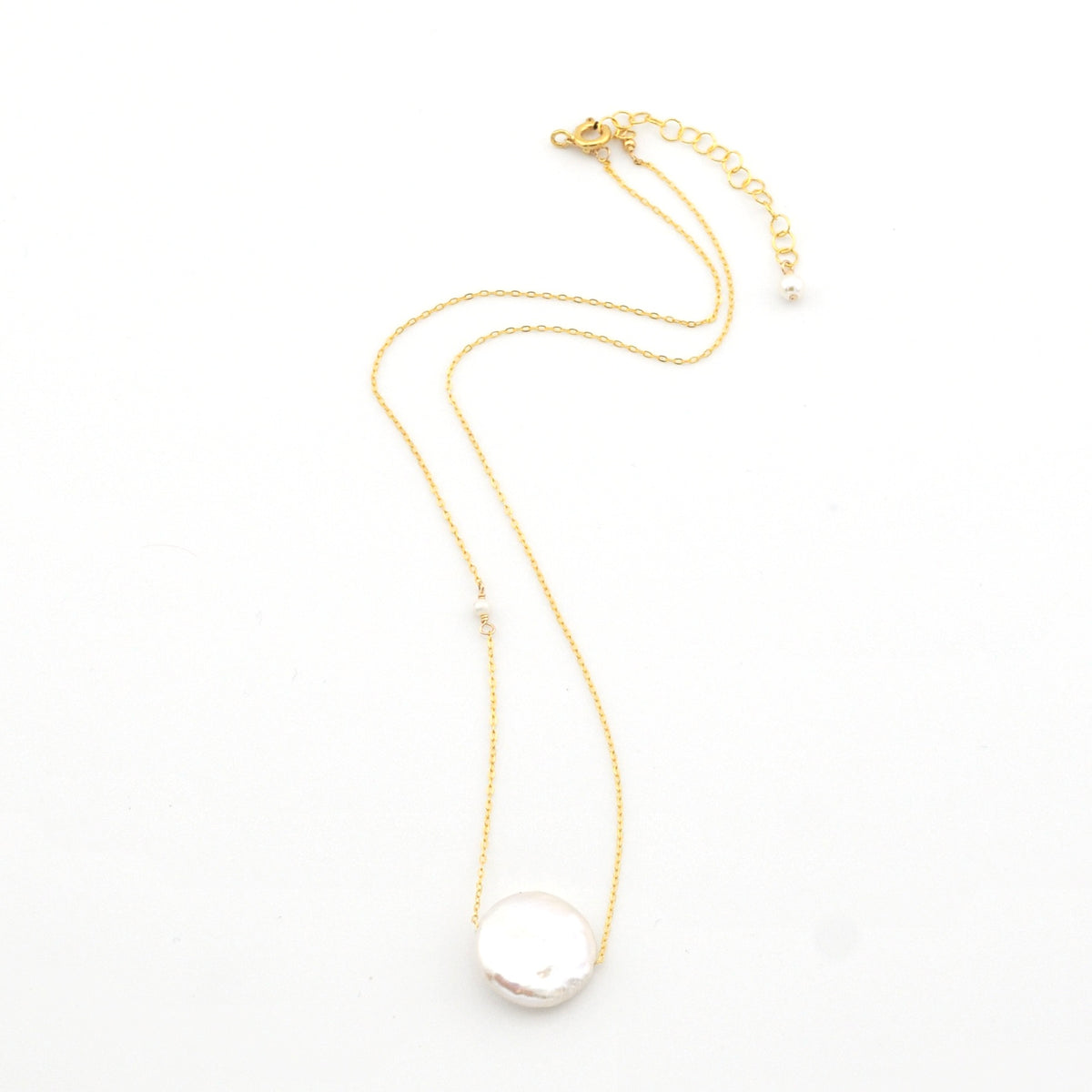 Gold necklace with a large pearl pendant on a white background