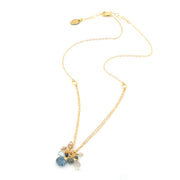 A delicate gold chain necklace with a small cluster of faceted gemstone charms in light blue, dark blue, and clear, displayed on a clean white background.
