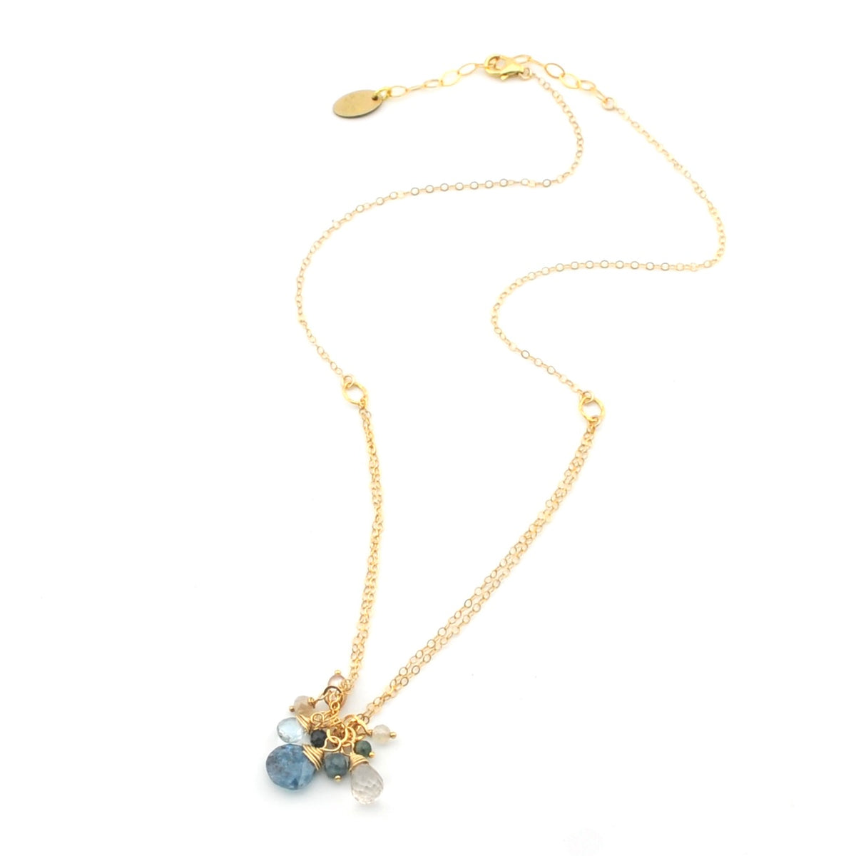 A delicate gold chain necklace with a small cluster of faceted gemstone charms in light blue, dark blue, and clear, displayed on a clean white background.