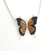 Butterfly-shaped pendant on a chain against a white background