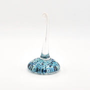 Glass ring holder with blue and white speckled design on a white background