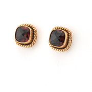 Pair of gold earrings with red gemstones on a white background