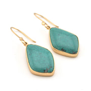 Turquoise earrings with gold frames on a white background