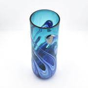 A tall, cylindrical glass vase with a swirled blue and teal pattern, photographed on a clean white background.