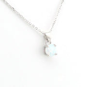 A silver chain necklace with a small oval pendant featuring a white opal-like gemstone in a silver prong setting, shown on a plain white background.