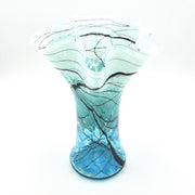 A hand-blown glass vase with a flared, ruffled top and a bulbous base, featuring a color gradient from light aqua at the top to bright blue at the bottom, with black and dark gray vein-like lines throughout.