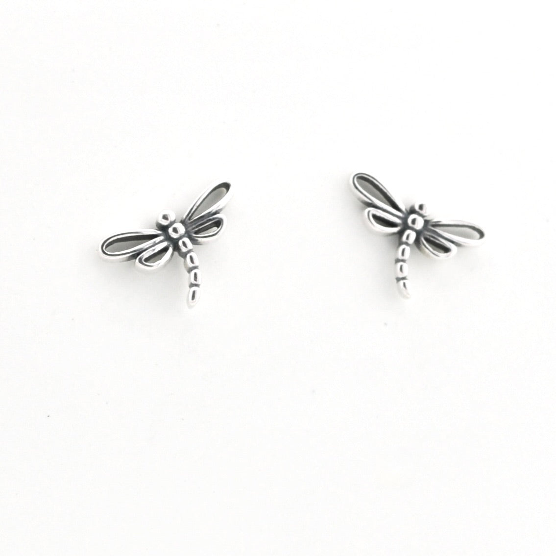 A pair of silver dragonfly stud earrings on a plain white background.