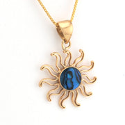 Gold sun-shaped pendant with a blue center on a white background