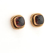 Pair of gold earrings with red gemstones on a white background