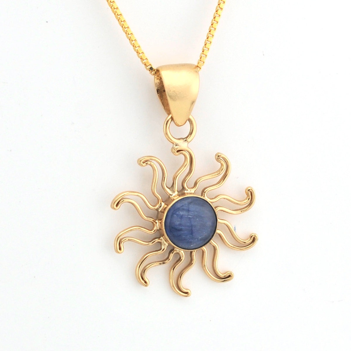 Gold sun-shaped pendant with a blue stone on a white background