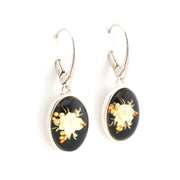Pair of earrings with black oval stones featuring floral designs on a white background