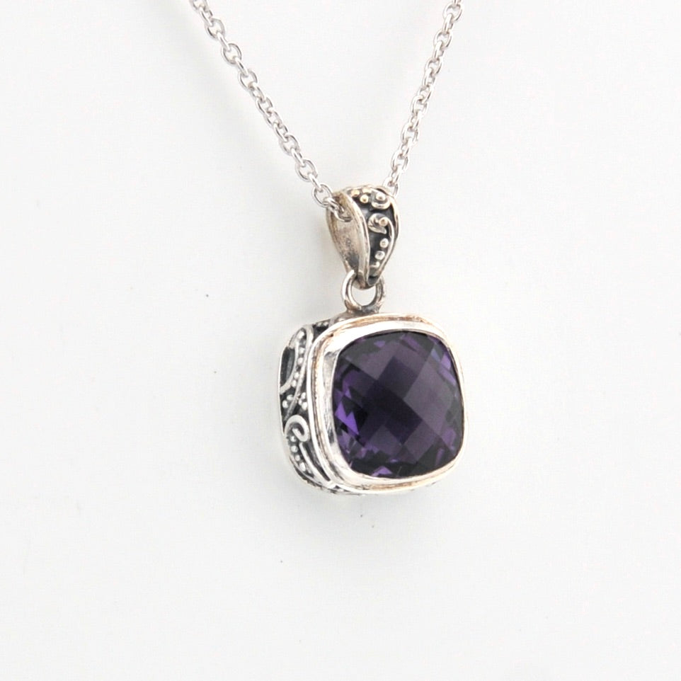 Silver pendant with a purple gemstone on a white background