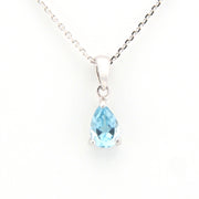 Teardrop-shaped blue gemstone pendant on a silver chain against a white background