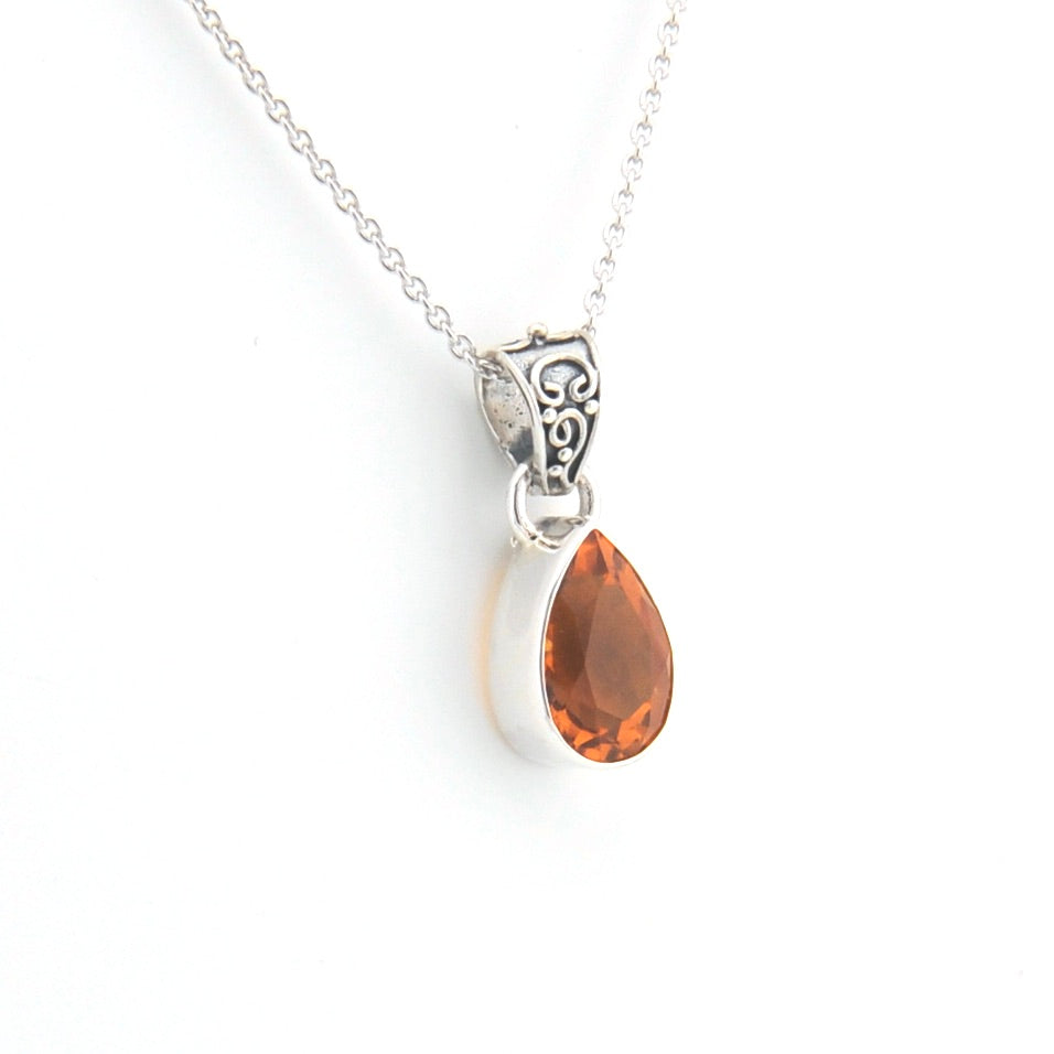 Teardrop-shaped pendant with golden gemstone on a silver chain against a white background