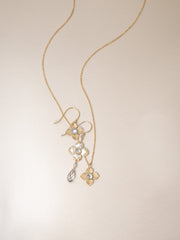 Gold necklace with floral pendant on a beige background