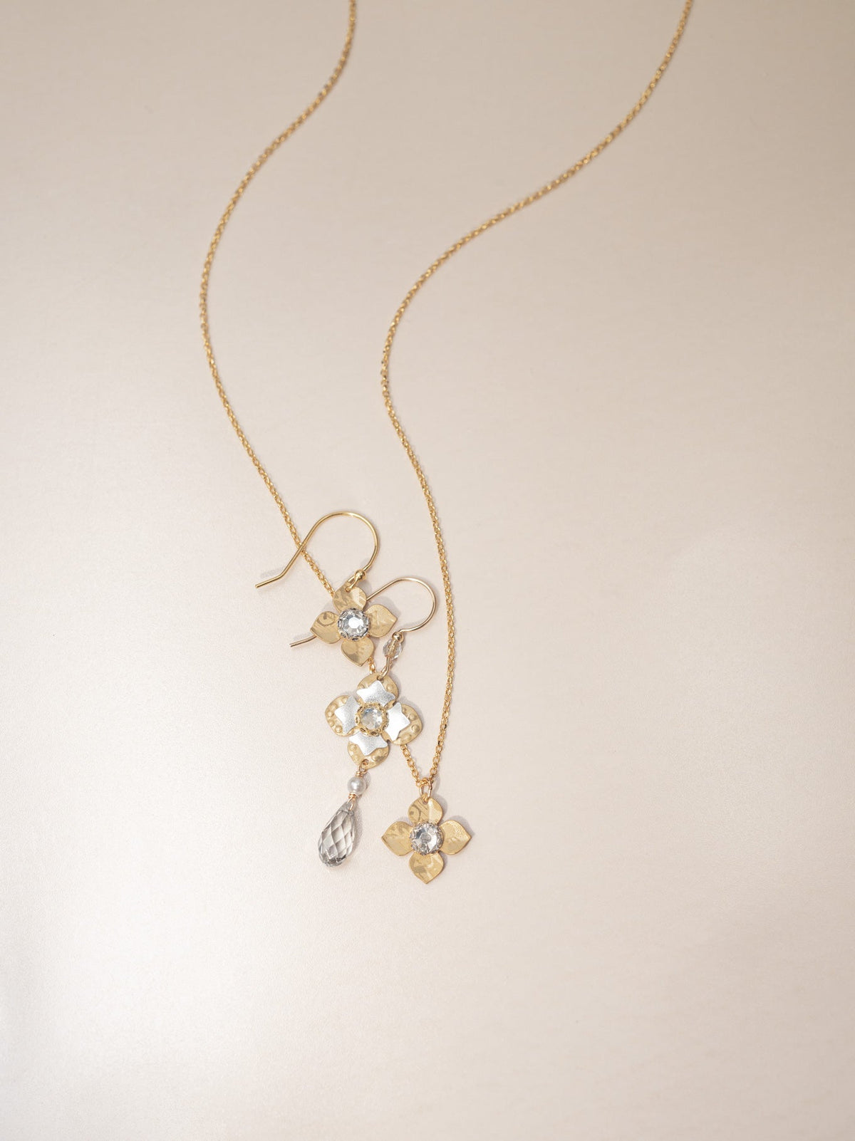 Gold necklace with floral pendant on a beige background