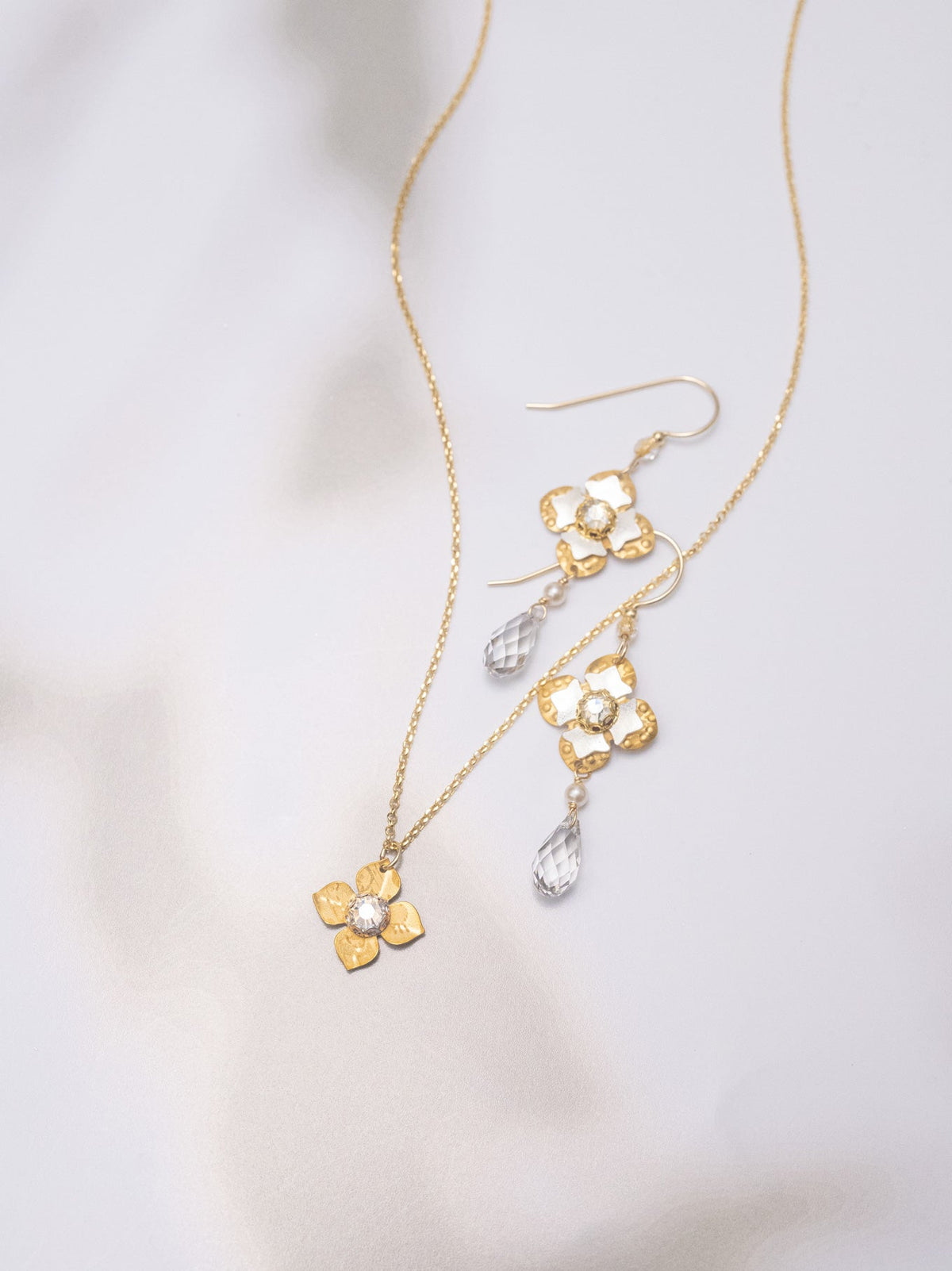 Gold necklace and earrings on a light gray background