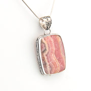 Pink stone pendant with silver frame on a white background
