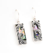 Silver earrings with wave design and abalone shell inlay on a white background