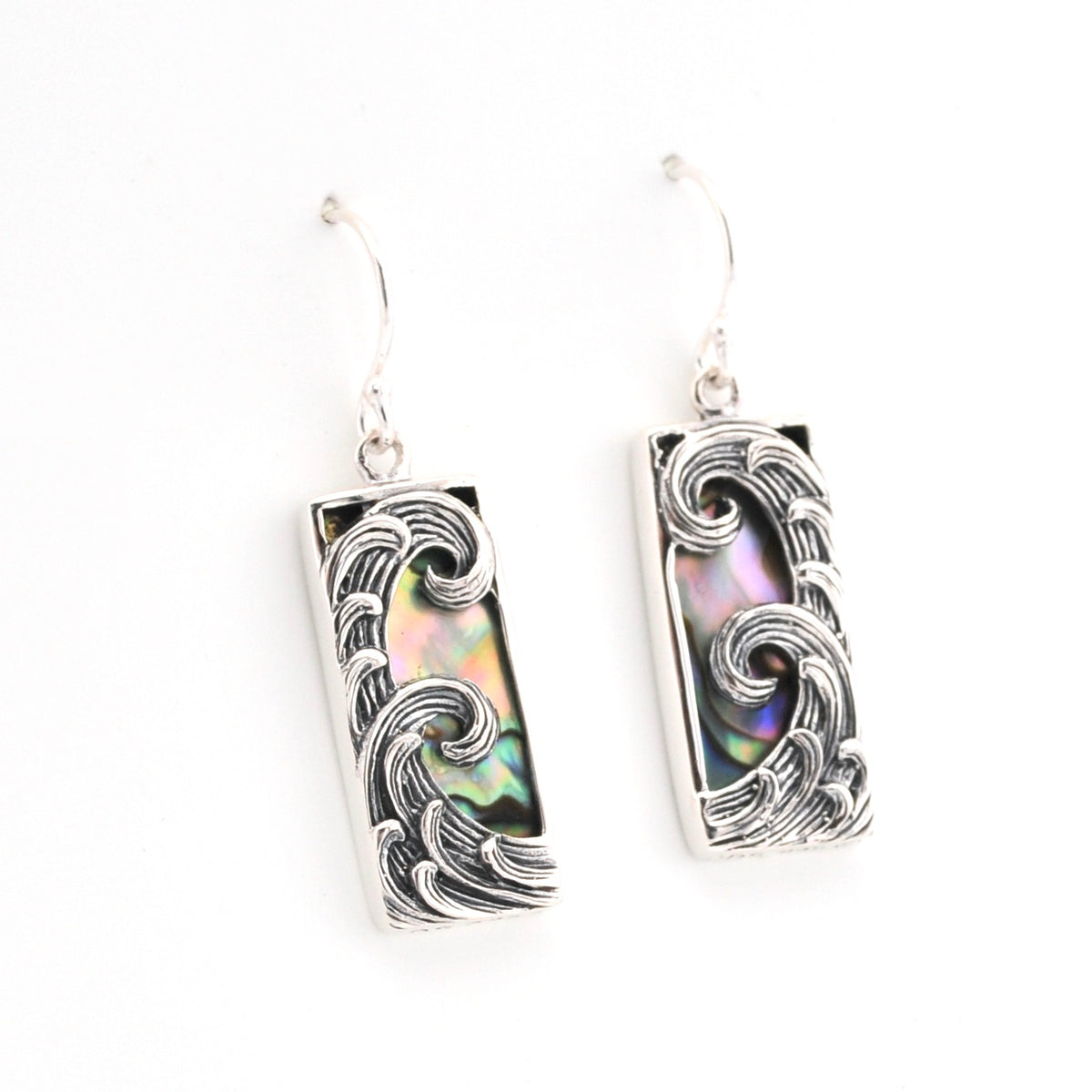 Silver earrings with wave design and abalone shell inlay on a white background