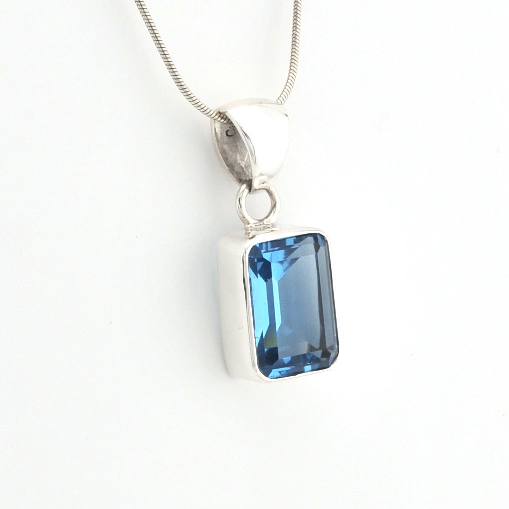 Blue gemstone pendant on a silver chain against a white background