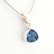 Silver pendant with a blue gemstone on a white background