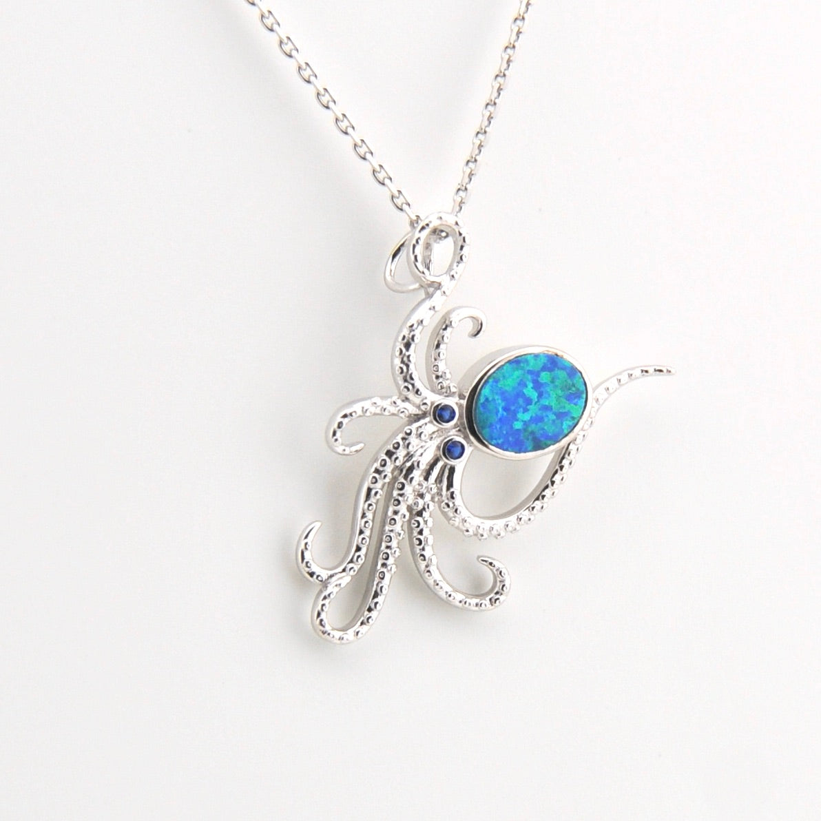 Silver octopus pendant with a blue opal stone on a white background