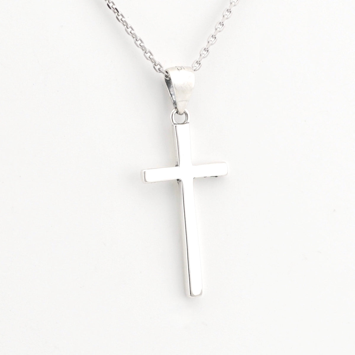Silver cross pendant on a chain against a white background