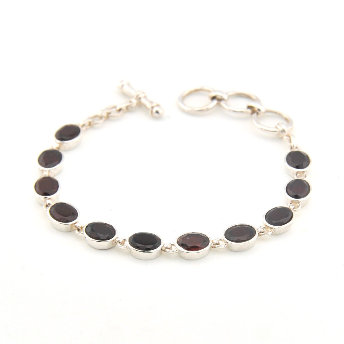 Silver bracelet with garnet oval on a white background