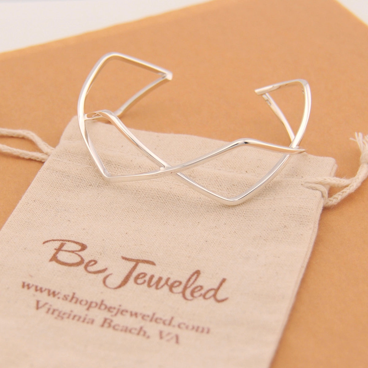 Silver cuff bracelet on a 'Be Jeweled' branded pouch.