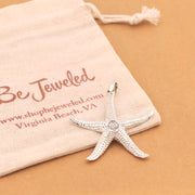 Silver starfish pendant on a Be Jeweled pouch with a beige background