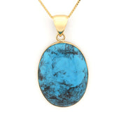 Gold necklace with a blue stone pendant on a white background