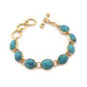 Gold bracelet with turquoise stones on a white background