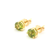 Gold earrings with green gemstones on a white background