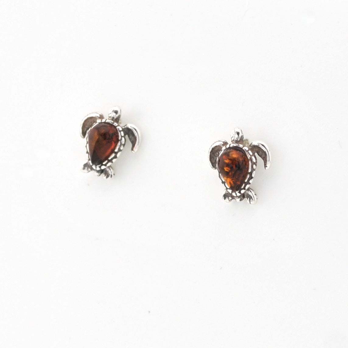 Pair of turtle-shaped earrings with amber stones on a white background