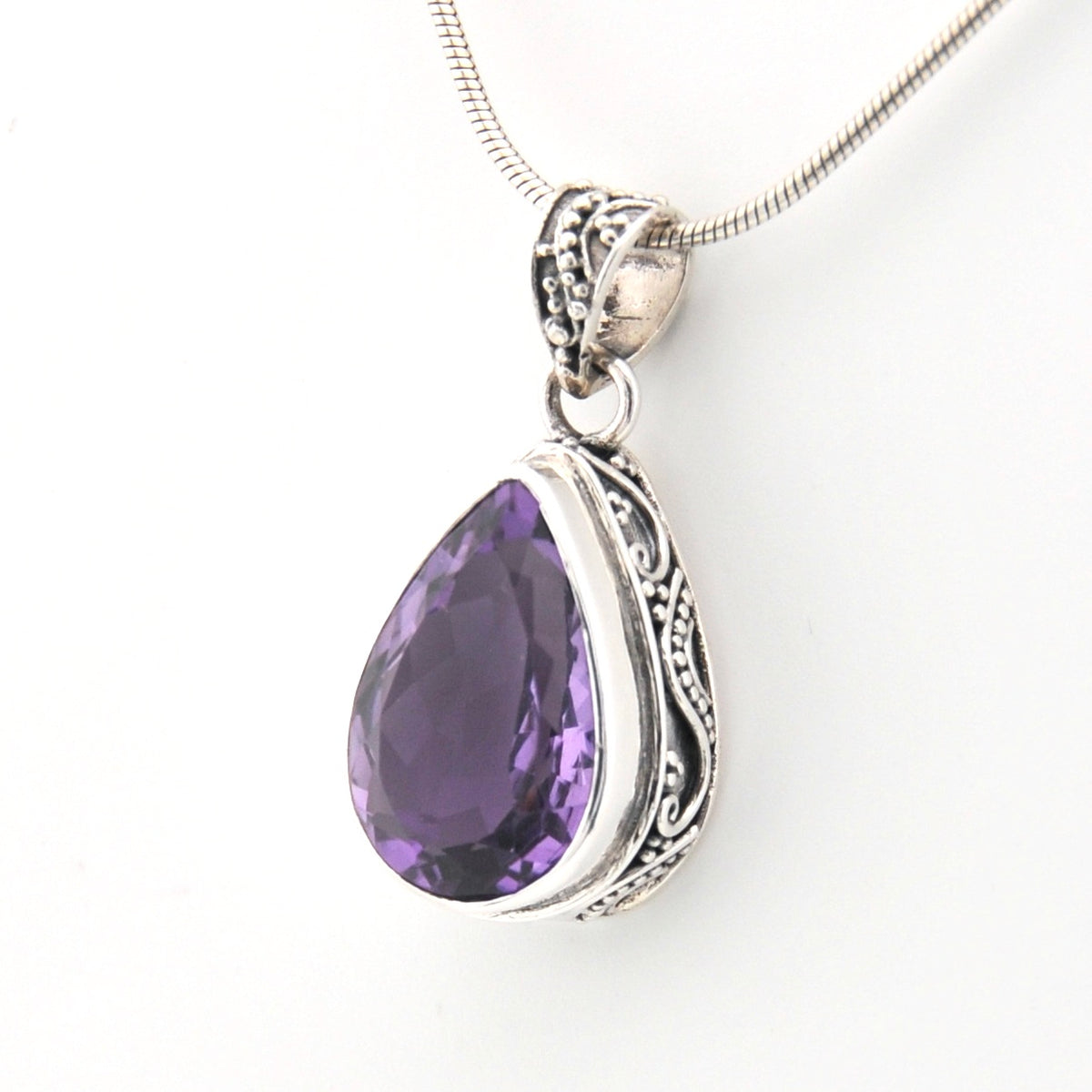 Purple teardrop pendant with silver setting on a white background