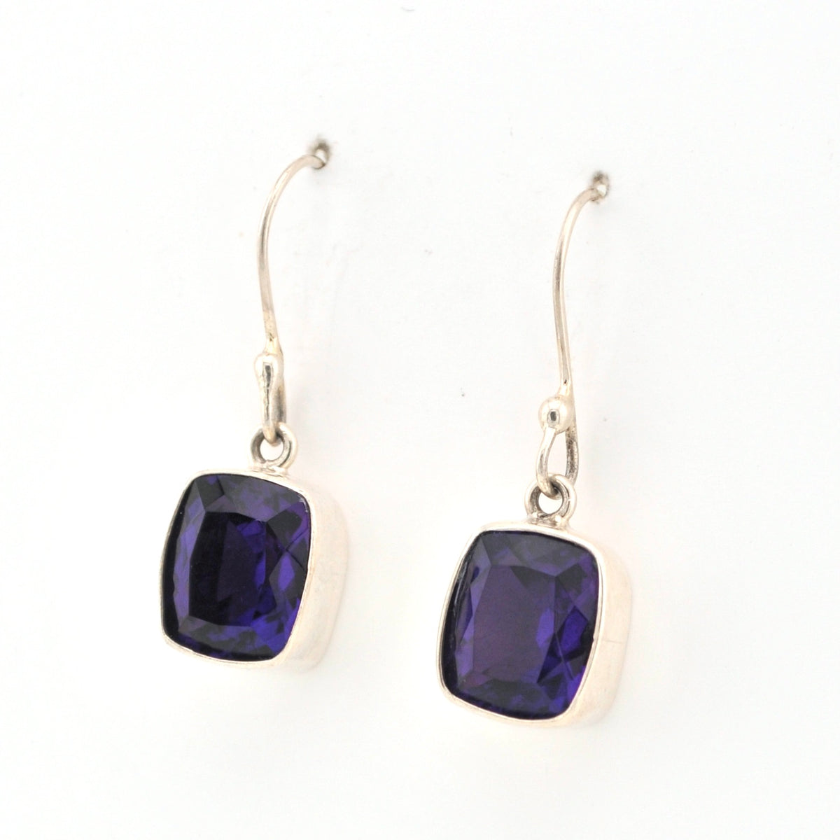 Pair of silver earrings with purple gemstones on a white background