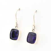 Pair of silver earrings with purple gemstones on a white background