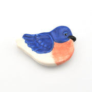 Decorative ceramic bird with blue and pink colors on a white background
