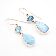 Pair of earrings with blue teardrop stones on a white background