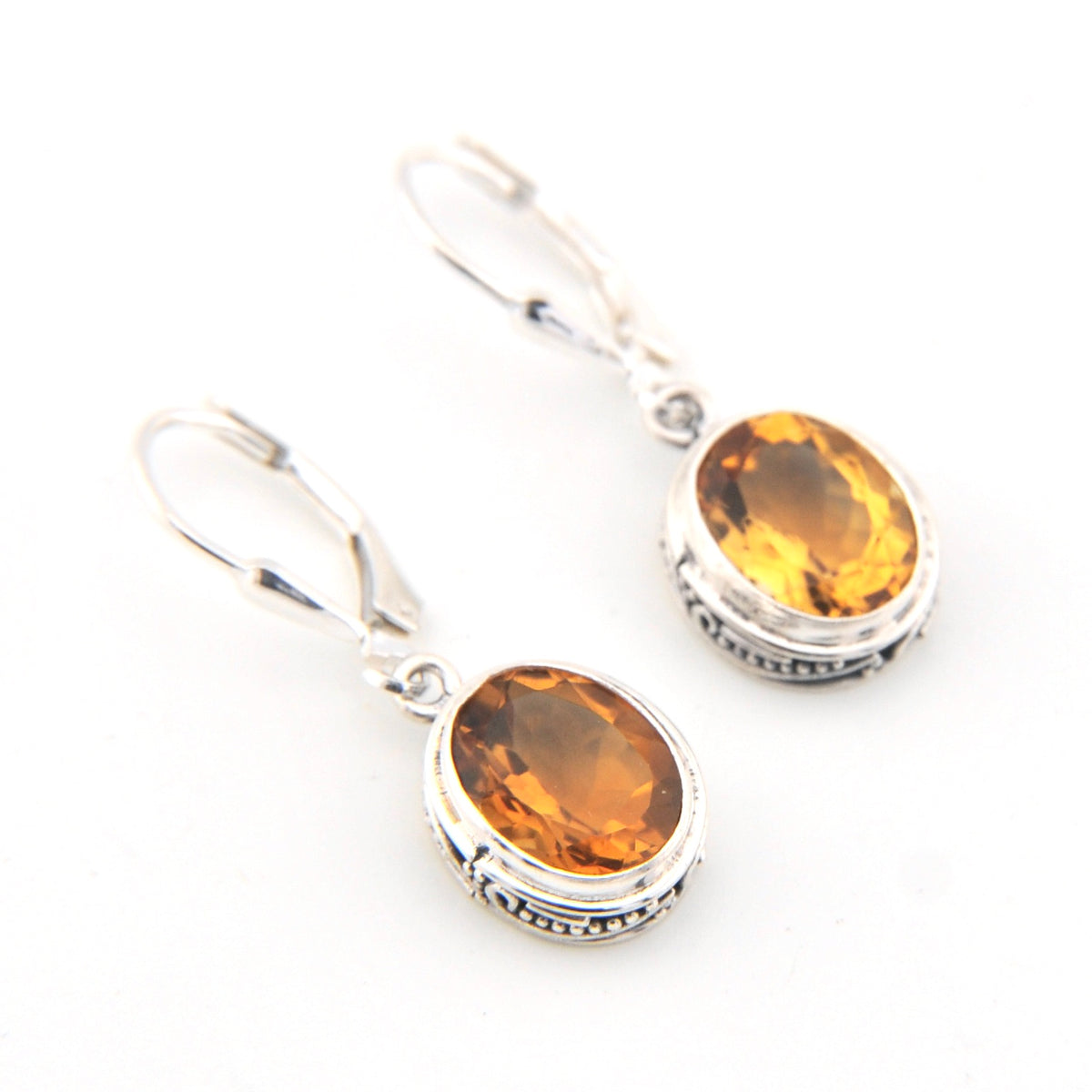 Pair of silver earrings with amber stones on a white background