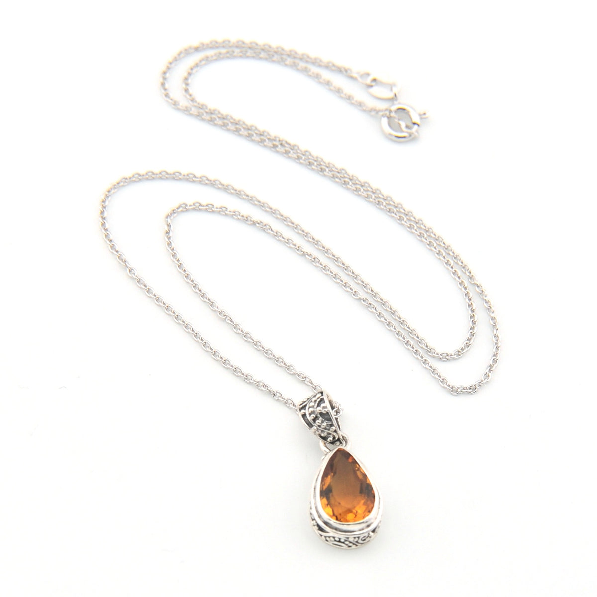 Silver necklace with a teardrop-shaped amber pendant on a white background