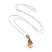Silver necklace with a teardrop-shaped amber pendant on a white background