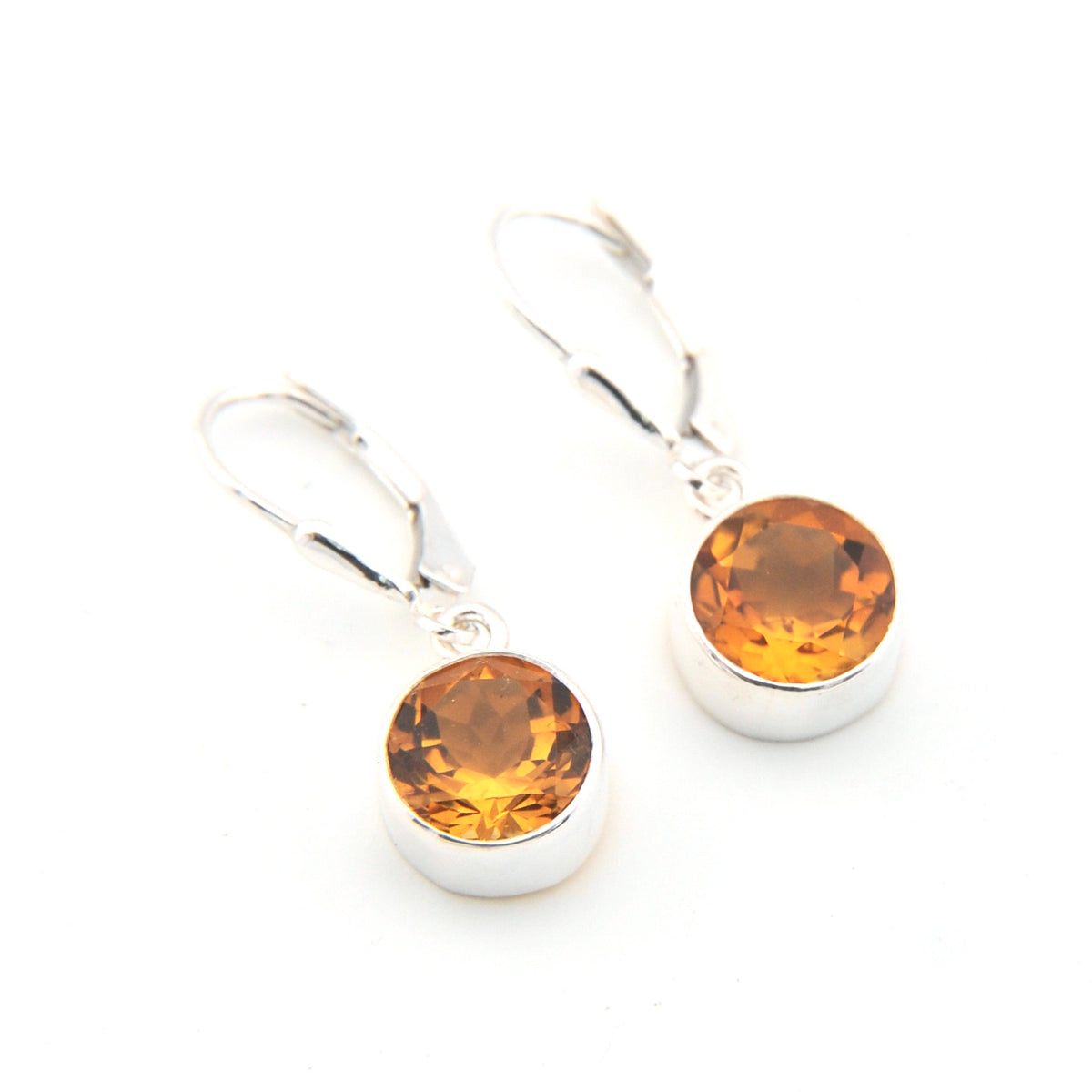 Silver earrings with round amber stones on a white background