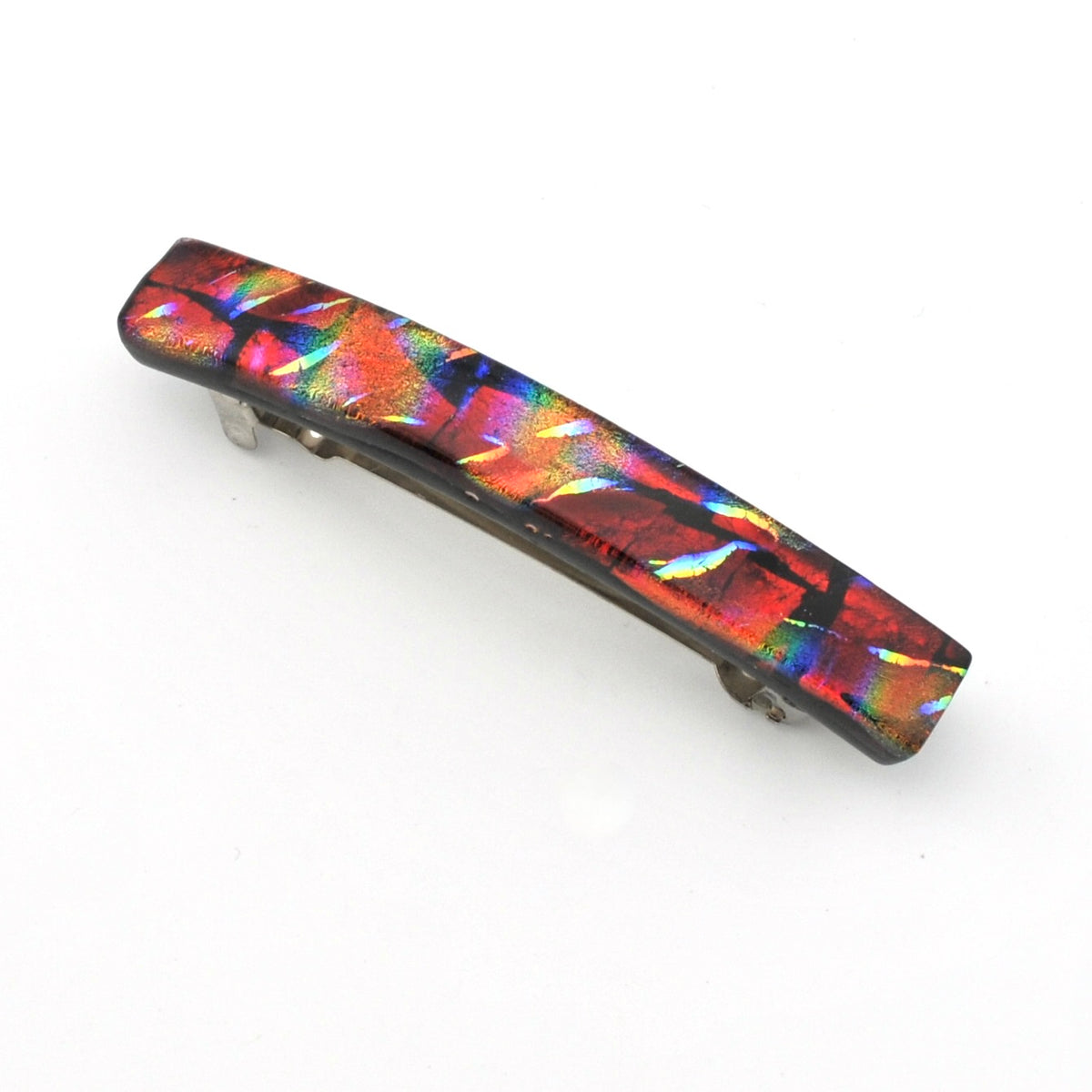A long, curved hair barrette featuring an iridescent, dichroic glass with a rainbow of colors including red, orange, yellow, green, and blue on a dark metal base, set against a plain white background.