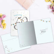 Greeting card with celebratory design on a white surface with flowers.