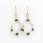 A pair of gold-tone dangle earrings with open teardrop-shaped hoops, decorated with faceted dark green beads, small white pearls, and clear glass beads on a white background.