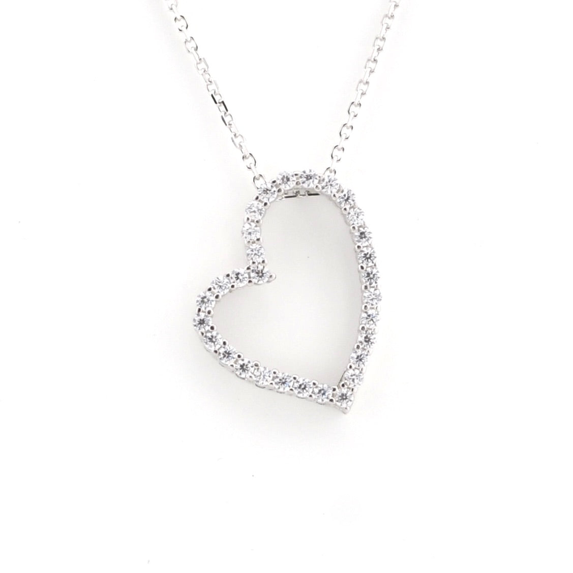 A silver heart-shaped pendant necklace paved with small clear stones, suspended from a delicate silver chain against a plain white background.