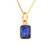 Gold necklace with a blue gemstone pendant on a white background